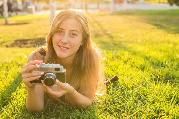 Mooi meisje liggend op het gras met vintage camera. — Stockfoto