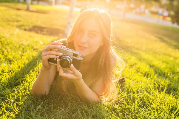 Hezká dívka ležící na trávě s vintage camera. — Stock fotografie