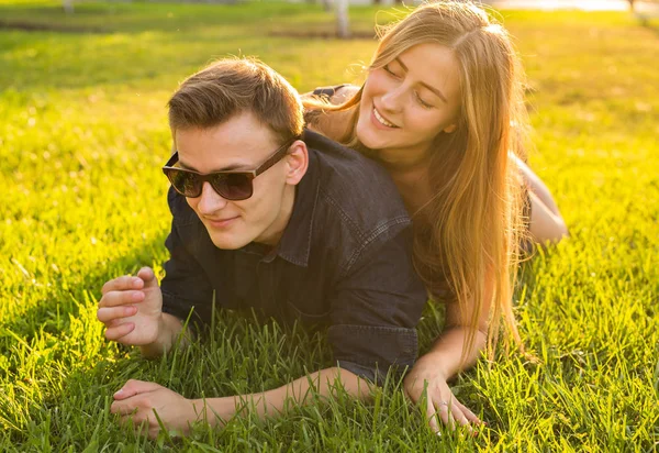 Conceito de diversão e amor com um jovem casal deitado na grama e sorrindo — Fotografia de Stock