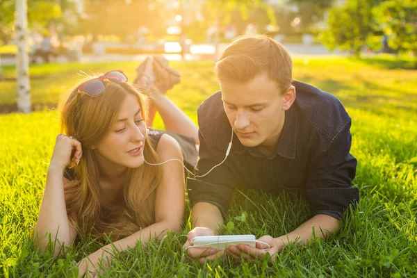 Verão, amor e conceito de pessoas - close-up de casal adolescente feliz deitado na grama com fones de ouvido e ouvir música . — Fotografia de Stock