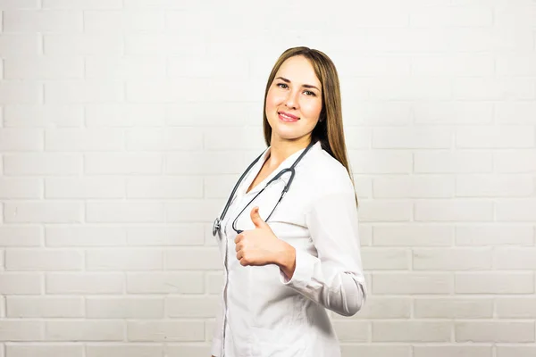 Ευτυχισμένη χαμογελαστό γυναίκα γιατρό προβολή αντίχειρες επάνω χέρι διαφήμιση κειμένου ή συνδεθείτε χειρονομία, στο γραφείο, με κενό copyspace περιοχή για σύνθημα. Υγειονομική περίθαλψη, ιατρικής, εργαστήριο συμβουλευτικής και εξετάσεων έννοια. — Φωτογραφία Αρχείου