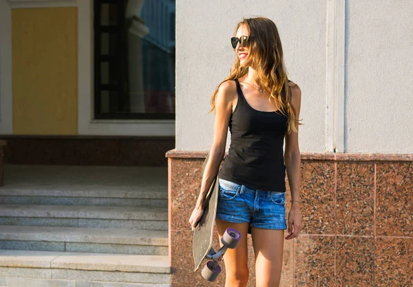 Menina hipster bonita com skate bordo usando óculos de sol — Fotografia de Stock