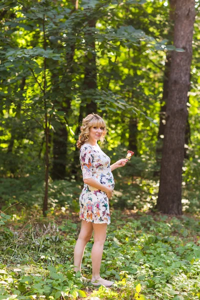 Portrait complet d'une jeune femme enceinte tenant une sucette en pleine nature estivale — Photo
