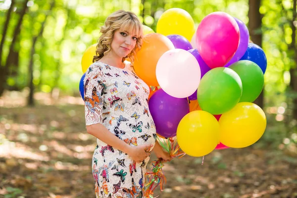 Jonge zwangere vrouw houdt van kleurrijke ballonnen buitenshuis — Stockfoto