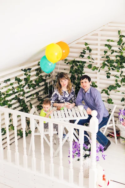 Família, paternidade, feliz aniversário e conceito de férias - pais felizes e criança a uma mesa bebendo chá e comendo bolo . — Fotografia de Stock