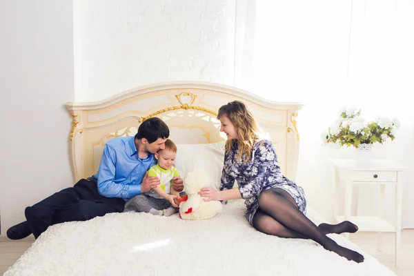Rodina, rodičovství a děti koncept - šťastná matka, otec a syn hraje na posteli v ložnici doma společně medvídek. — Stock fotografie