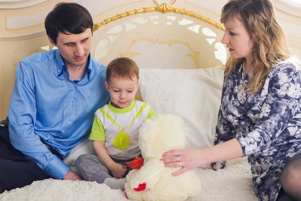 Rodzina, rodzicielstwo i dzieci koncepcja - szczęśliwa matka, ojciec i syn gra razem z misiem na łóżko w sypialni w domu. — Zdjęcie stockowe