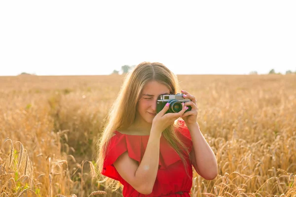 Jonge vrouw in het veld met vintage camera. — Stockfoto