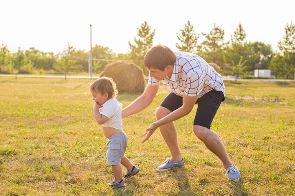 Счастливый смеющийся мальчик, играющий на природе с отцом — стоковое фото