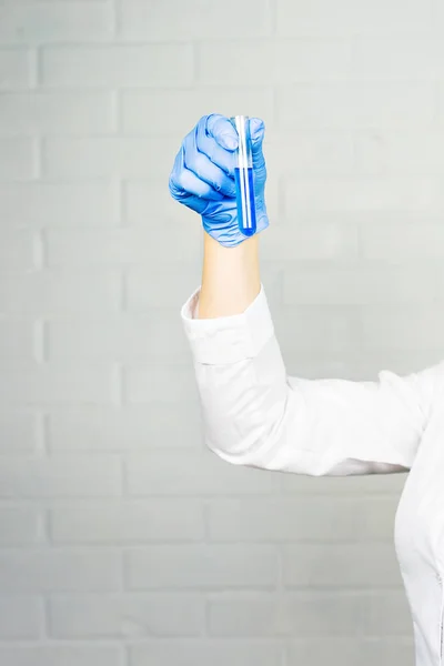 Γκρο πλαν του χεριού του ιατρικός ερευνητής γυναίκα κρατώντας το δοκιμαστικό σωλήνα με μπλε υγρό — Φωτογραφία Αρχείου