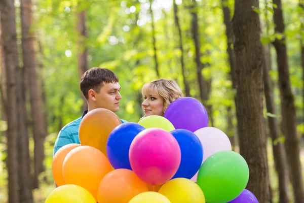 Férias de verão, celebração e namoro conceito - casal com balões coloridos ao ar livre — Fotografia de Stock