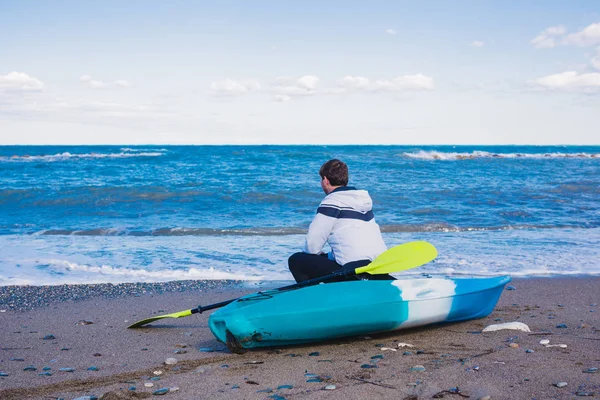 Hombre sentado en la playa con kayak — Foto de Stock