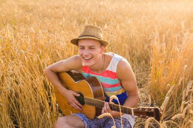 Bir adam alanında gitar çalıyor, gün güneş ışığı ile sakin ol.