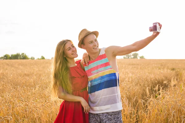 Unga lyckliga paret tar en selfie i fältet — Stockfoto