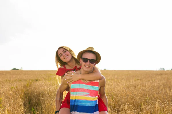 Ευτυχισμένο ζευγάρι έχοντας υπαίθρια διασκέδαση στο πεδίο σιτάρι. Γελά μαζί χαρούμενη οικογένεια. Έννοια ελευθερία. Piggyback — Φωτογραφία Αρχείου