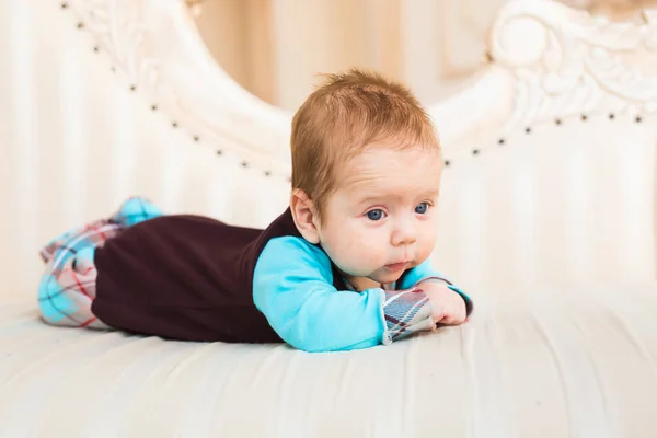 Adorable niño con el pelo rojo y los ojos azules. Recién nacido lyling en sofá . —  Fotos de Stock