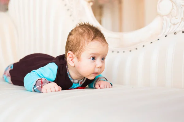 Adorable niño con el pelo rojo y los ojos azules. Recién nacido lyling en sofá . —  Fotos de Stock