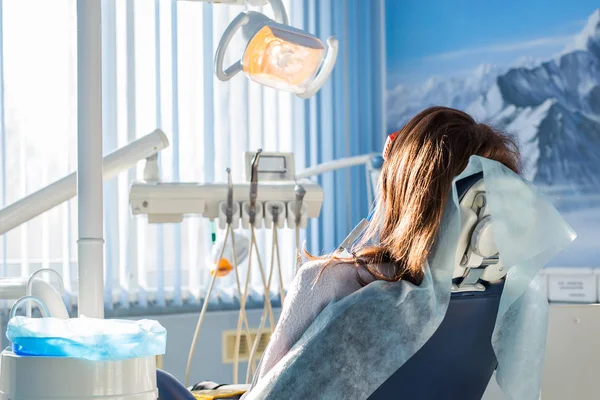 若い女性患者訪問歯科オフィス歯科の椅子に座っての背面します。クリニック口腔病学 — ストック写真