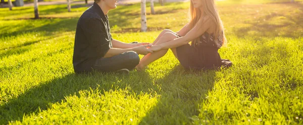 Freundschafts- und Liebeskonzept mit einem jungen Paar, das im Gras sitzt und aus nächster Nähe spricht — Stockfoto