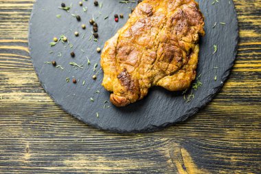 Izgara domuz biftek siyah taş zemin üzerine.