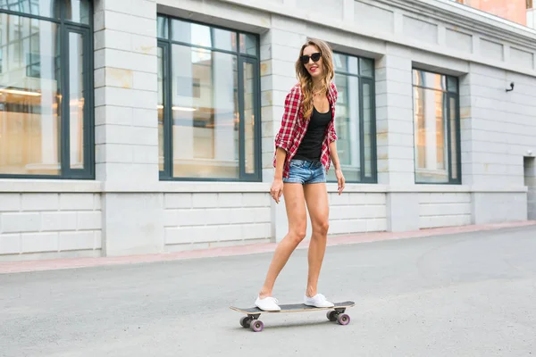 Летние каникулы, экстремальный спорт и люди концепция - счастливая девушка верхом на современном скейтборде на улице города — стоковое фото