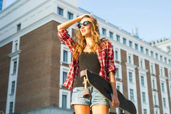 Mooie hipster meisje met skate board dragen van een zonnebril — Stockfoto