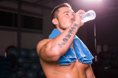 bir şişe su içme spor salonunda genç beyaz vücut geliştirmeci.