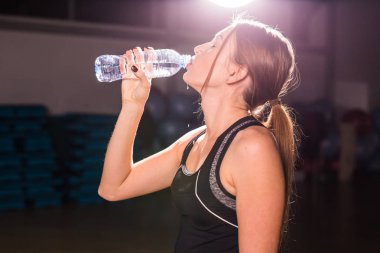 Fitness kadın içme suyu şişe. Kas genç erkek spor salonunda egzersiz bir mola.