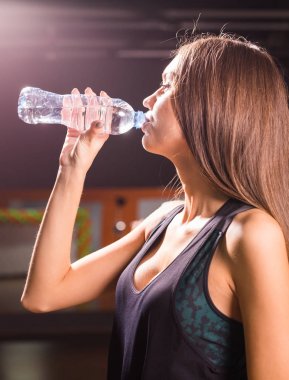 Fitness kadın içme suyu şişe. Kas genç erkek spor salonunda egzersiz bir mola.