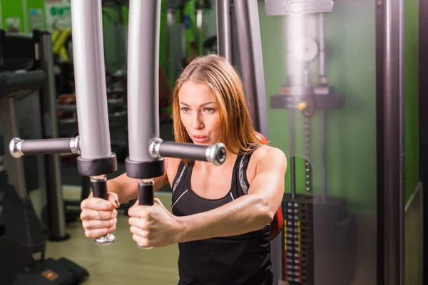Genç fitness kadın spor salonunda egzersiz egzersiz makinesi ile yürütmek