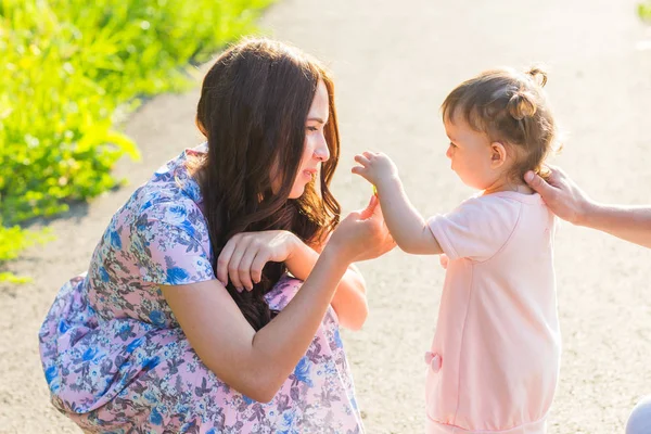 Hija pequeña dando flores a la madre en el parque —  Fotos de Stock