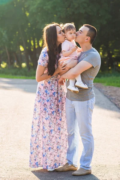 Genitori baciare la loro piccola figlia all'aperto in estate — Foto Stock