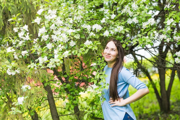 Retrato de uma jovem mulher sorrindo no jardim florido na primavera. Flores de árvore de maçã flores . — Fotografia de Stock