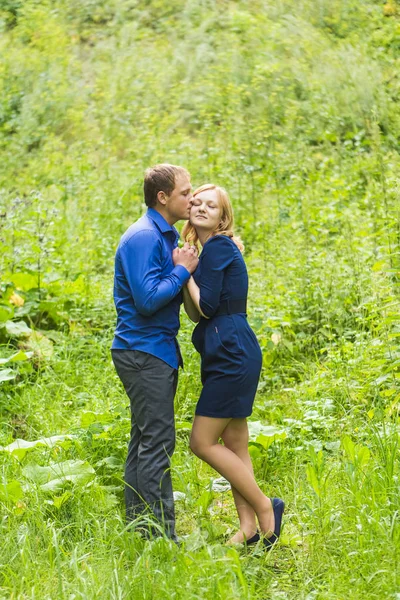 Jovem casal amoroso abraçando ao ar livre na grama verde — Fotografia de Stock