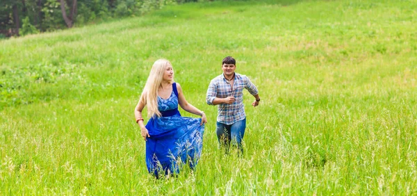 Молодой человек и женщина бегут по лугу с зеленой травой — стоковое фото