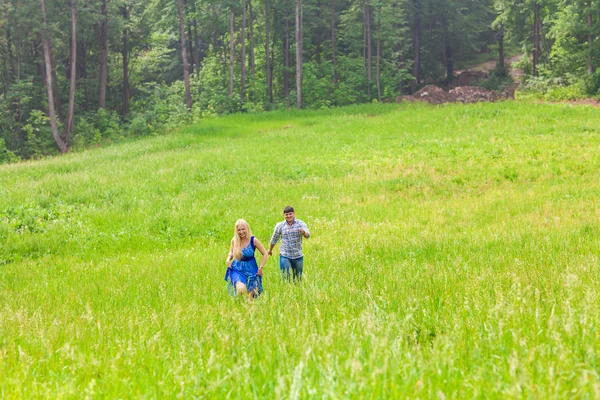 Młody mężczyzna i kobieta działa na wsi łąka z zielonej trawie — Zdjęcie stockowe