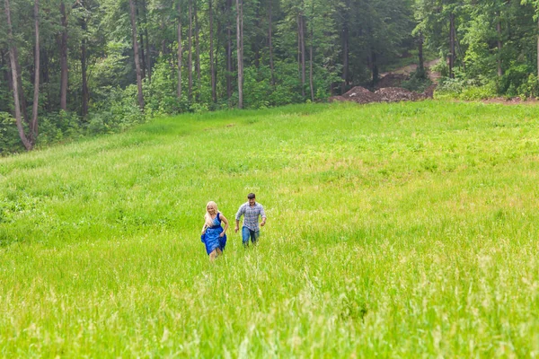 Młody mężczyzna i kobieta działa na wsi łąka z zielonej trawie — Zdjęcie stockowe
