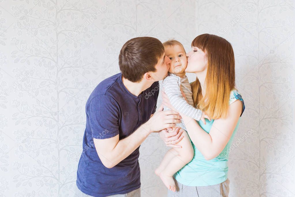 Young happy parents kissing baby boy