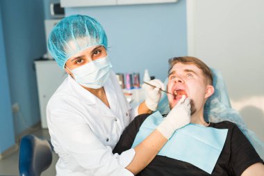 Diş hekimi bir hastaya diş tedavisi uyguluyor.