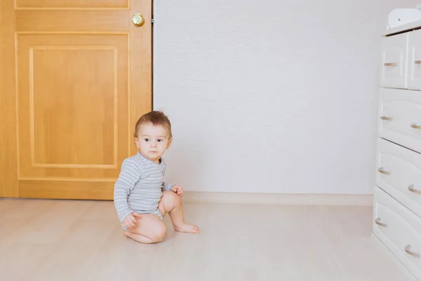 Söt baby pojke småbarn sitter på golvet i sovrummet — Stockfoto