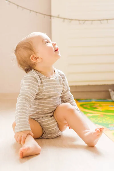 Söt baby pojke småbarn sitter på golvet i sovrummet — Stockfoto