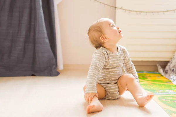 Söt baby pojke småbarn sitter på golvet i sovrummet — Stockfoto