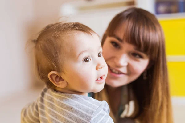 Närbild porträtt av glada mor med bedårande baby boy inomhus — Stockfoto