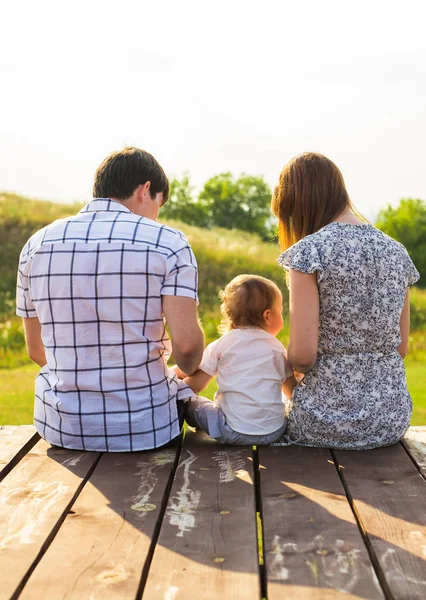Bakifrån av mor, far och son sitter tillsammans utomhus — Stockfoto