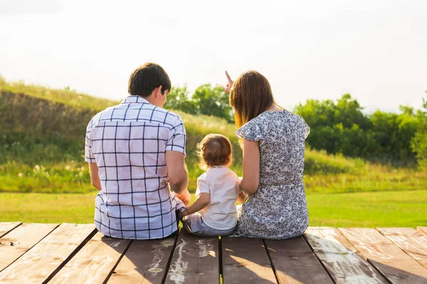 Rear view of mother, father and son sitting together outdoors — Stock Photo, Image