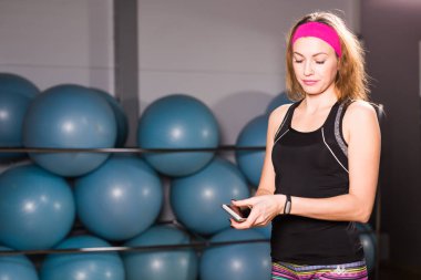 Genç kadın fitness izci ve smartphone içinde jimnastik salonu ile