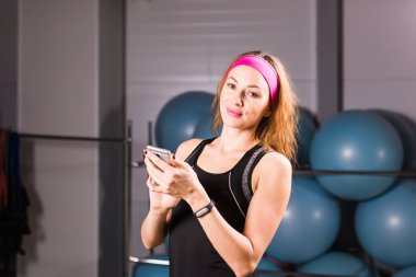 Spor, fitness, teknoloji ve insan kavramı - etkinlik izleyicisi ve smartphone içinde jimnastik salonu olan kadın