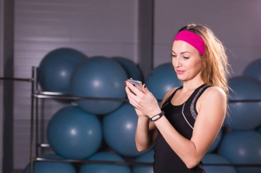 Spor, fitness, teknoloji ve insan kavramı - etkinlik izleyicisi ve smartphone içinde jimnastik salonu olan kadın