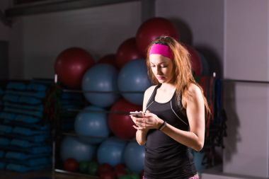 Spor, fitness, teknoloji ve insan kavramı - etkinlik izleyicisi ve smartphone içinde jimnastik salonu olan kadın