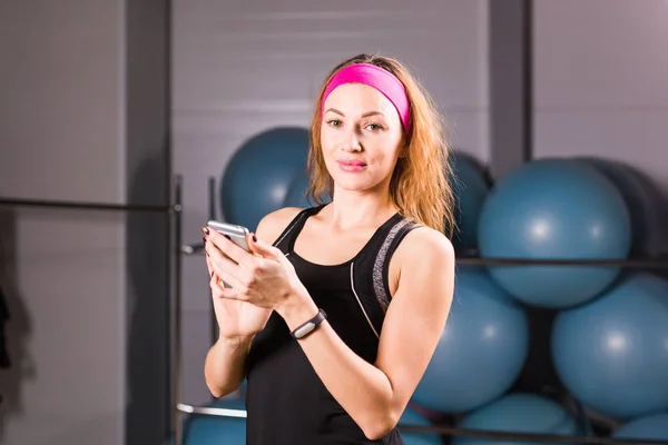 Fiatal nő található fitness tracker és smartphone-ban tornaterem — Stock Fotó